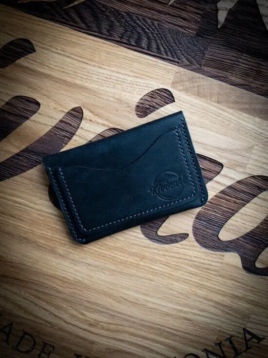 handmade black vegetable tanned leather card wallet with a flap closure and an outer pocket