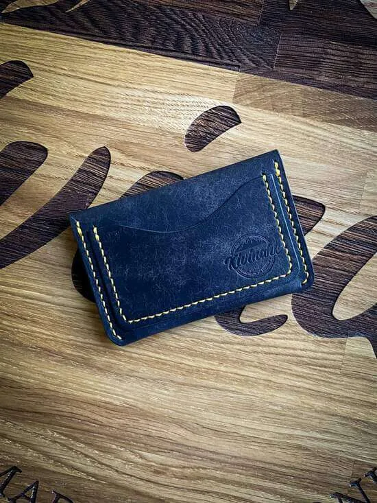 Handmade blue vegetable tanned leather card wallet with a flap closure and striking yellow stitching